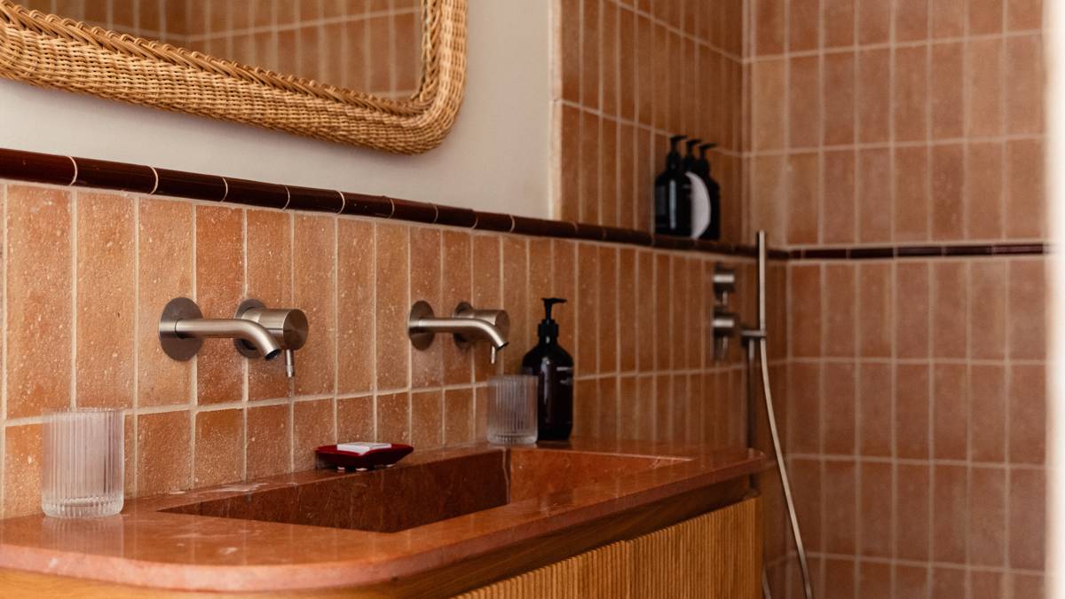 Des bouteilles soigneusement disposées bordent l'étagère des toilettes, avec un miroir monté au-dessus du lavabo.