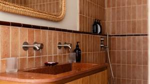Des bouteilles soigneusement disposées bordent l'étagère des toilettes, avec un miroir monté au-dessus du lavabo.
