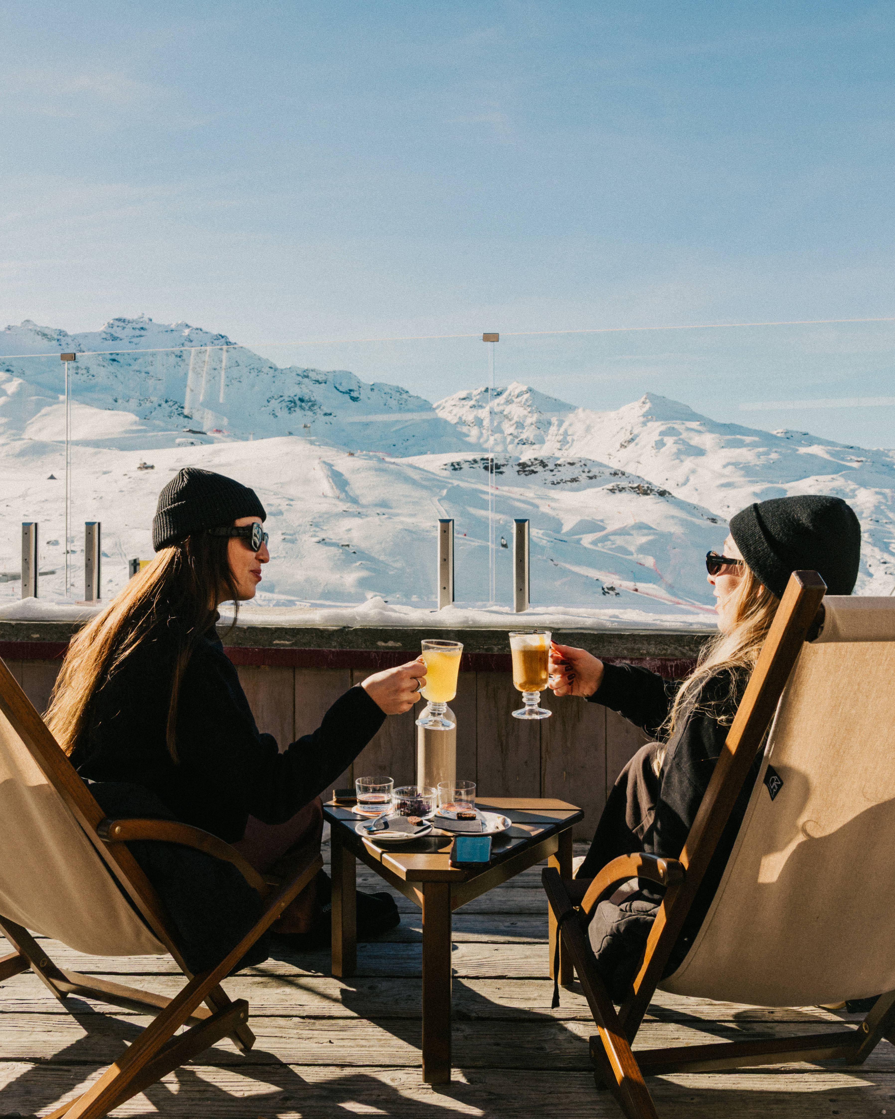 Freundinnen stoßen auf einer sonnigen Après-Ski-Terrasse in Val Thorens an, Beaumier
