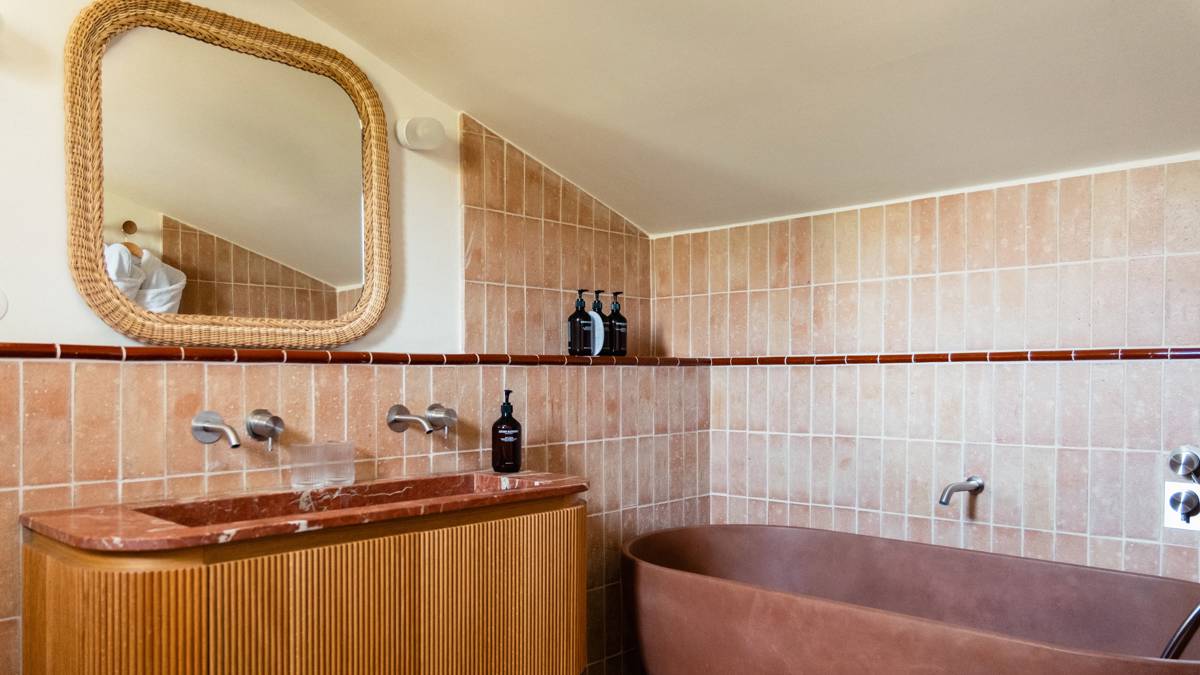 Une photo prise de la salle de bain montre un miroir monté et une baignoire sur la droite.