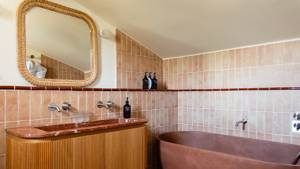 Une photo prise de la salle de bain montre un miroir monté et une baignoire sur la droite.