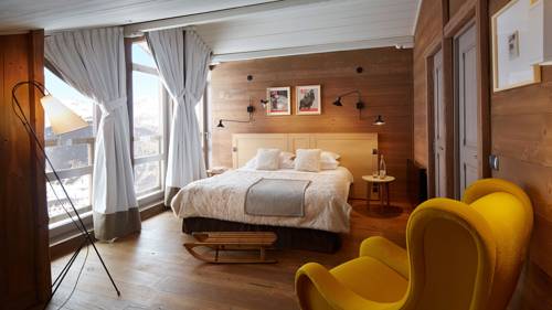 Une chambre bien organisée comprend un lit confortable, un canapé orange et deux portraits au-dessus.