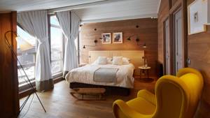 Une chambre bien organisée comprend un lit confortable, un canapé orange et deux portraits au-dessus.