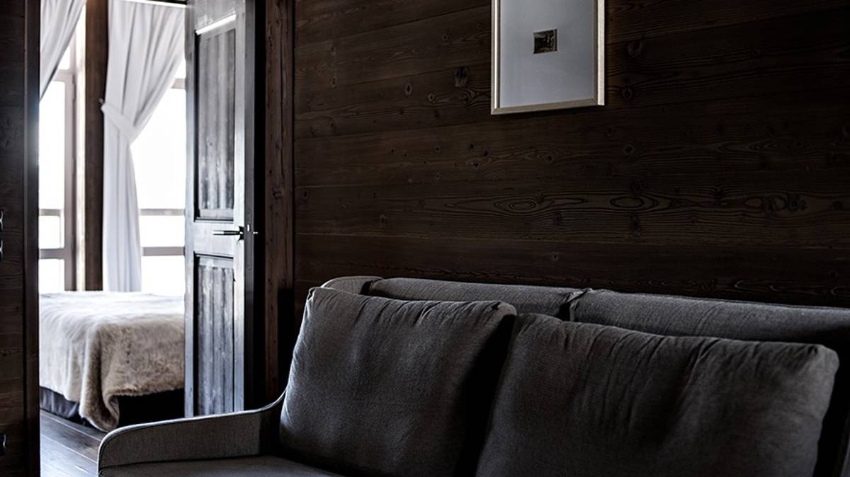 Un canapé confortable bien disposé près du mur en bois et un portrait monté juste au-dessus.