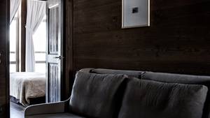Un canapé confortable bien disposé près du mur en bois et un portrait monté juste au-dessus.
