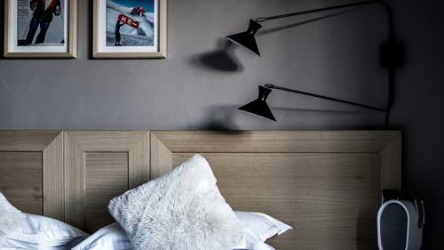 Une photo prise montre une lampe frontale murale et deux portraits au-dessus du lit.
