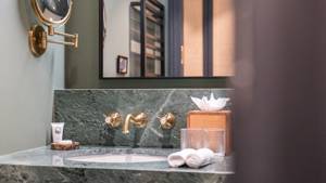 Badezimmer im Le Fitz Roy Val Thorens mit Waschtisch aus grünem Marmor, Messingarmaturen und beleuchtetem Spiegel