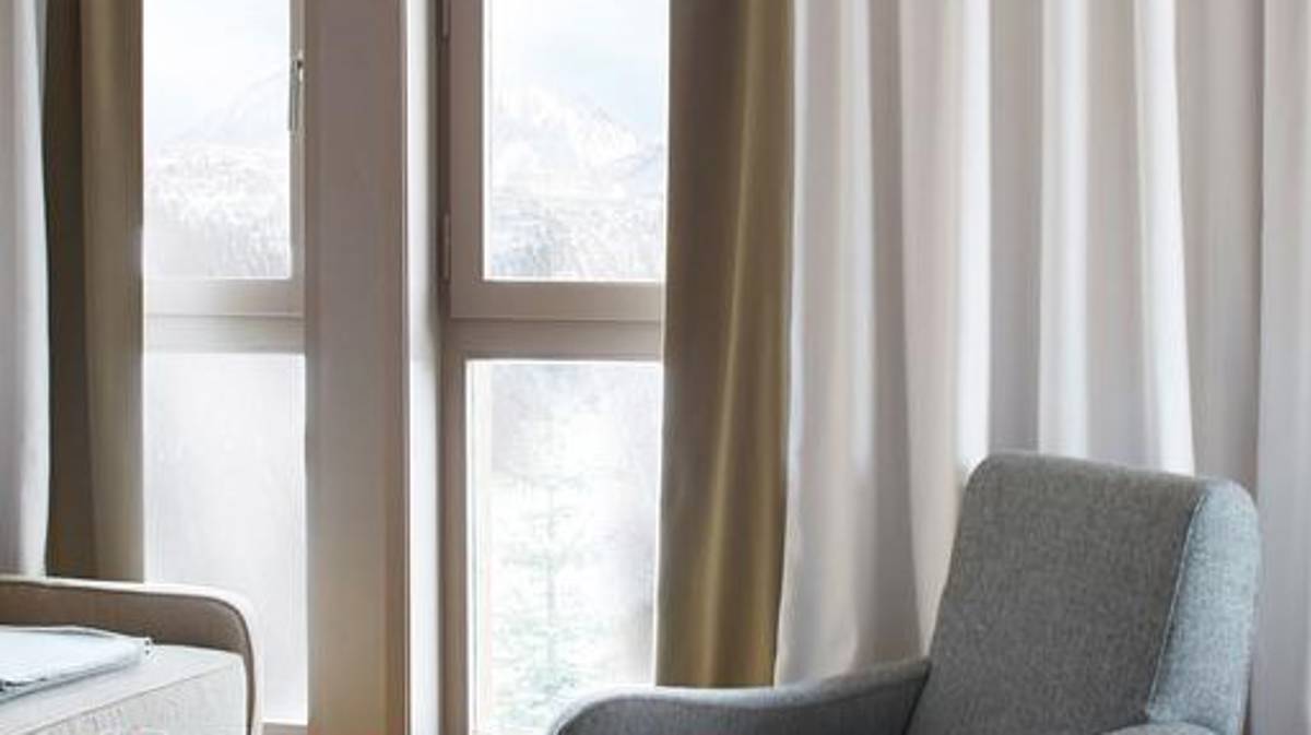 Une photo prise montre une chaise confortable placée près d'une porte recouverte d'un rideau.