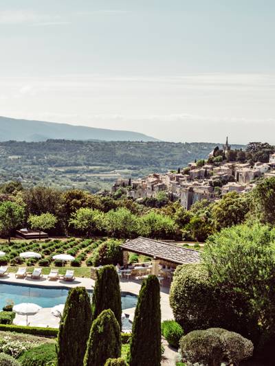 Pool and gardens of Hotel Capelongue with the village of Bonnieux and the Luberon valley in the background