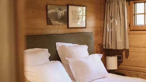 A cozy bed is placed by the wooden-finished wall with two portraits mounted above.