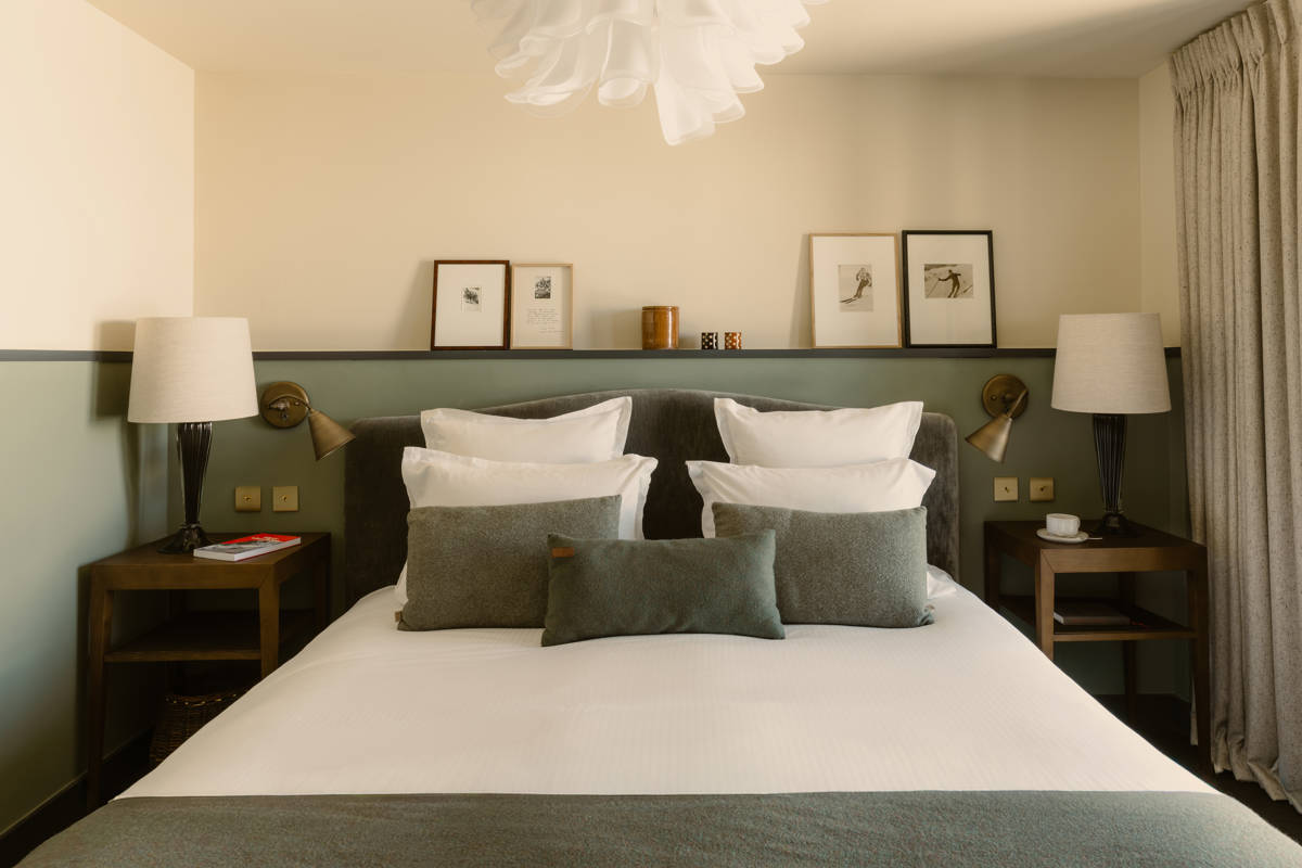 Doppelbett im Le Fitz Roy mit zwei Nachttischlampen und gerahmten alten Ski-Fotografien