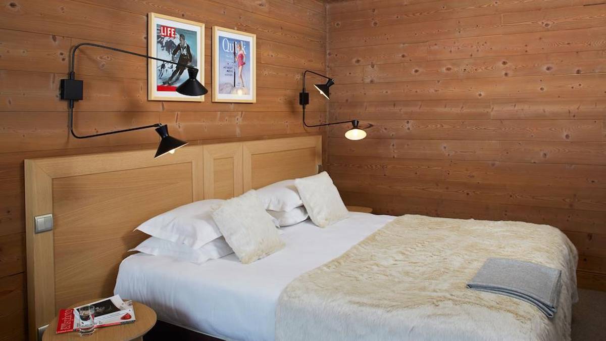 Une chambre bien rangée comprend un lit confortable avec une lampe frontale et deux portraits au-dessus.