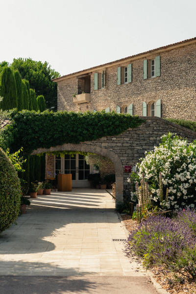 Stone entrance with lavender and flowering garden at the Beaumier hotel Capelongue in Bonnieux, Luberon