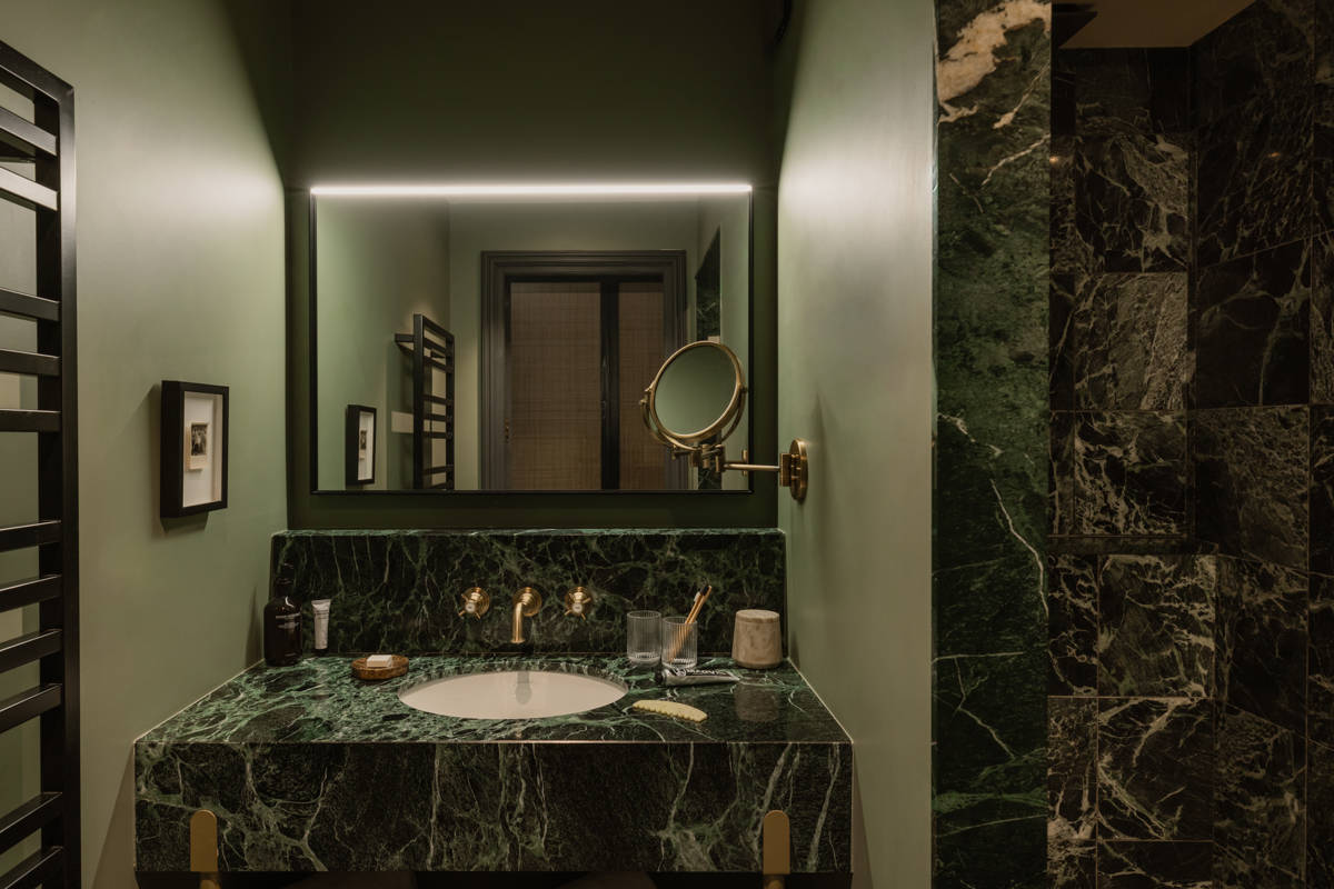 Badezimmer im Le Fitz Roy Val Thorens mit Waschtisch aus grünem Marmor, Messingarmaturen und beleuchtetem Spiegel