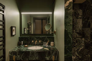 Badezimmer im Le Fitz Roy Val Thorens mit Waschtisch aus grünem Marmor, Messingarmaturen und beleuchtetem Spiegel