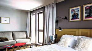 Une chambre bien organisée comprend un lit confortable, un canapé confortable et deux portraits au-dessus.