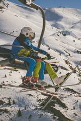 A couple of friends in a gondola going to ski