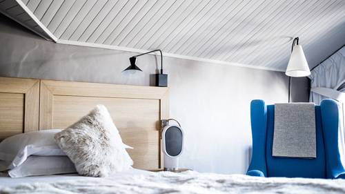 Un lit douillet avec des oreillers en plumes et un canapé de couleur bleue placé à proximité du lit.