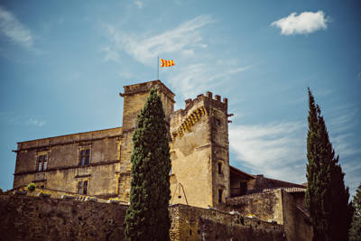 Château de Lourmarin, first Renaissance castle in Provence, flanked by cypress trees under a blue sky